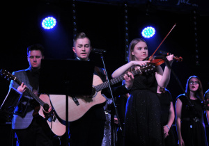 Zdjęcie przedstawia uczniów podczas występów grających na instrumentach